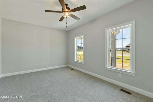 spare room featuring carpet, visible vents, baseboards, and ceiling fan