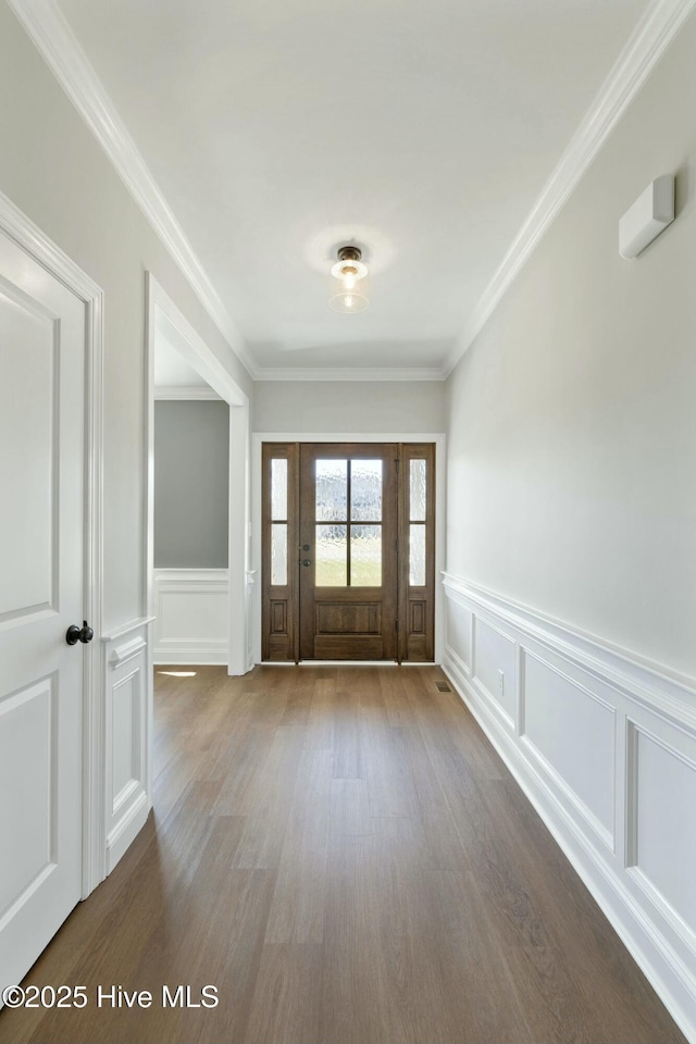 entrance foyer with a decorative wall, ornamental molding, a wainscoted wall, and dark wood-style flooring
