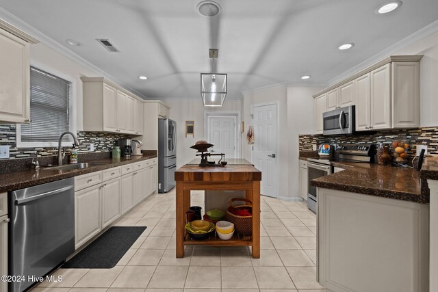 kitchen with appliances with stainless steel finishes, tasteful backsplash, ornamental molding, and sink