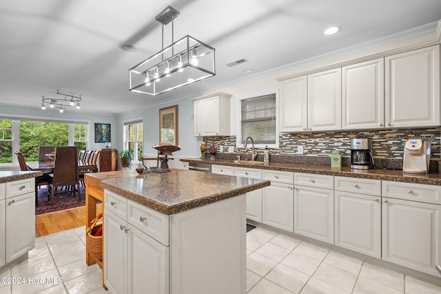 kitchen featuring white cabinetry, a center island, sink, hanging light fixtures, and ornamental molding