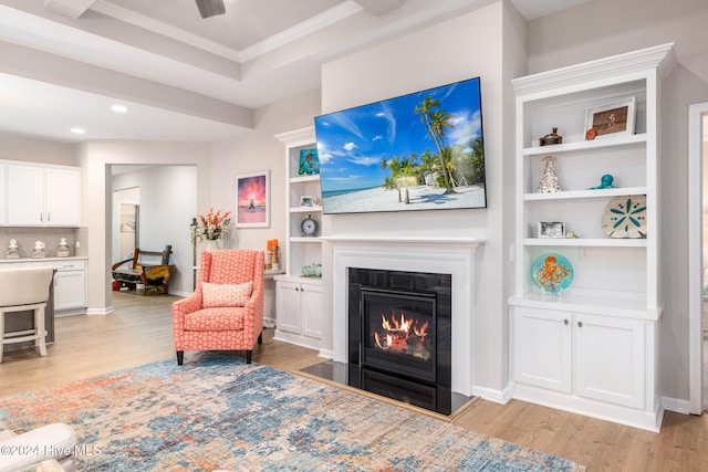 living room featuring built in shelves, light hardwood / wood-style flooring, and ornamental molding