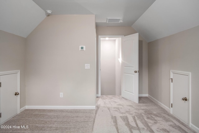 additional living space featuring light colored carpet and lofted ceiling