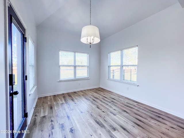 empty room featuring light wood-type flooring and vaulted ceiling