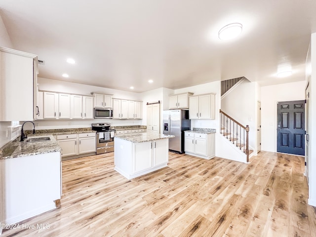 kitchen with a kitchen island, light stone countertops, sink, and appliances with stainless steel finishes