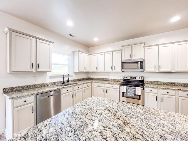 kitchen with white cabinets, light stone countertops, sink, and appliances with stainless steel finishes