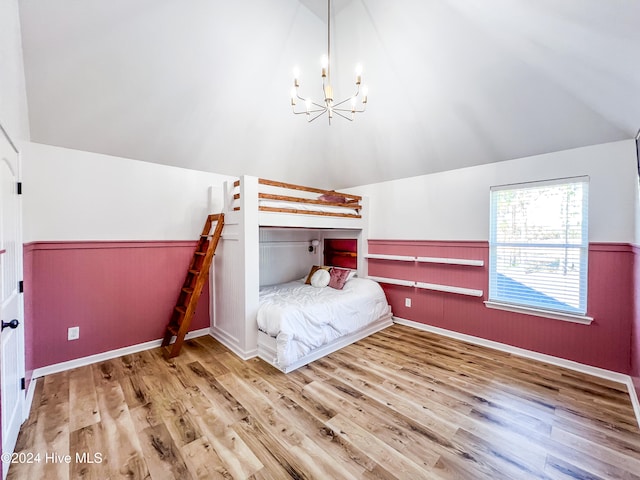 unfurnished bedroom featuring a chandelier, vaulted ceiling, and hardwood / wood-style flooring