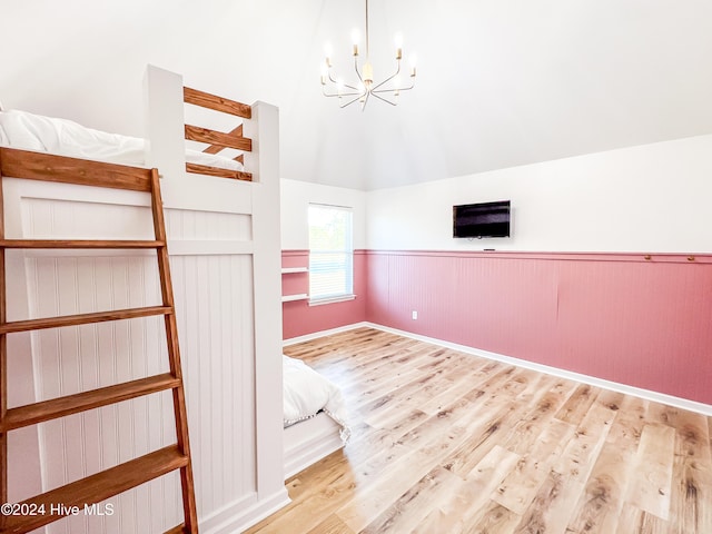 unfurnished bedroom with light wood-type flooring, vaulted ceiling, and an inviting chandelier