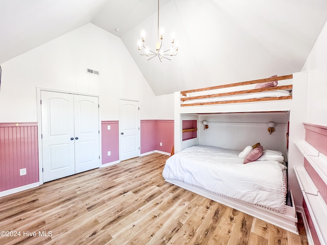 bedroom with a closet, an inviting chandelier, lofted ceiling, and light hardwood / wood-style flooring