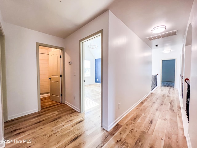 hallway with vaulted ceiling and light hardwood / wood-style flooring