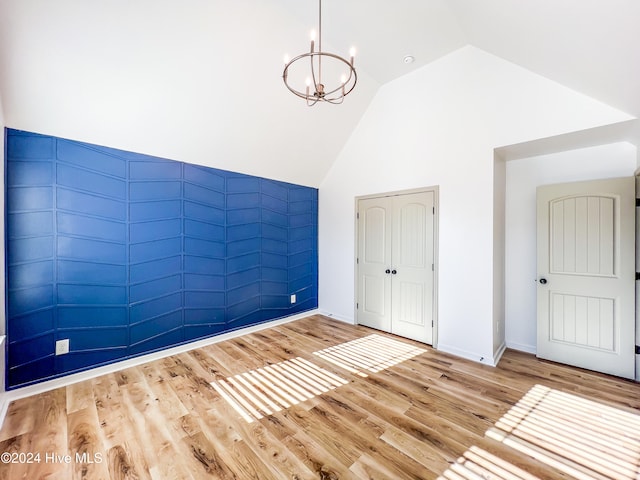 interior space featuring a closet, light wood-type flooring, lofted ceiling, and an inviting chandelier