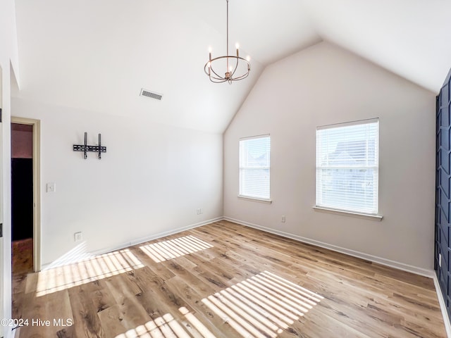 unfurnished room featuring light hardwood / wood-style floors, lofted ceiling, and an inviting chandelier