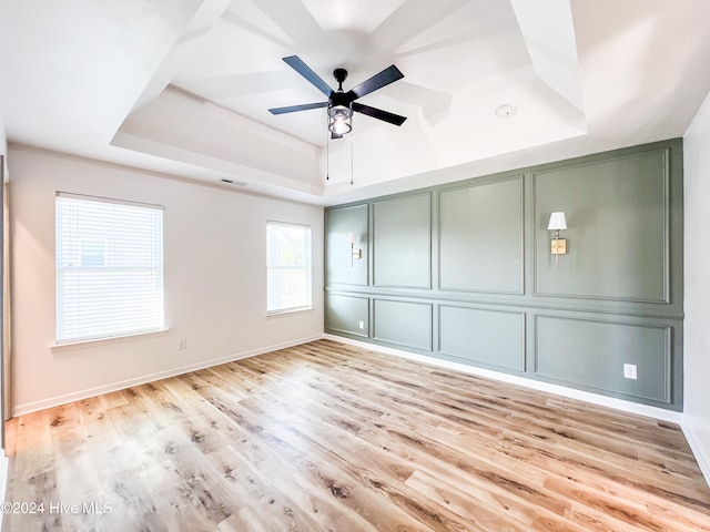 unfurnished room featuring a tray ceiling, ceiling fan, and light hardwood / wood-style flooring