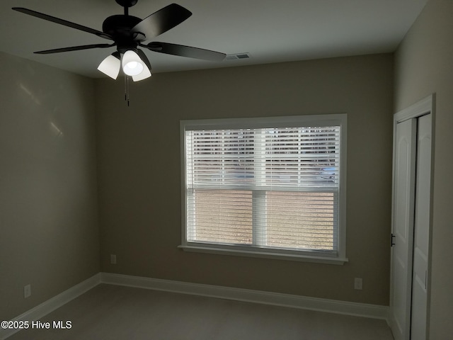 unfurnished room with visible vents, a healthy amount of sunlight, baseboards, and ceiling fan