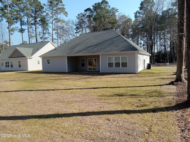 view of front of house featuring central air condition unit, roof with shingles, and a front yard