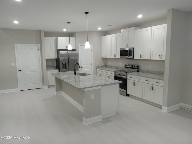 kitchen with sink, appliances with stainless steel finishes, an island with sink, light stone countertops, and white cabinets