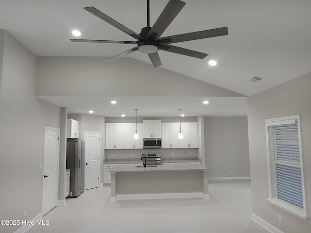 kitchen featuring pendant lighting, stainless steel appliances, light stone counters, white cabinets, and a center island with sink