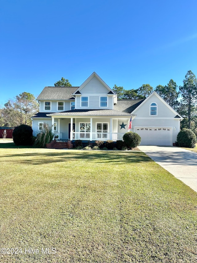 view of property featuring covered porch, a garage, and a front lawn