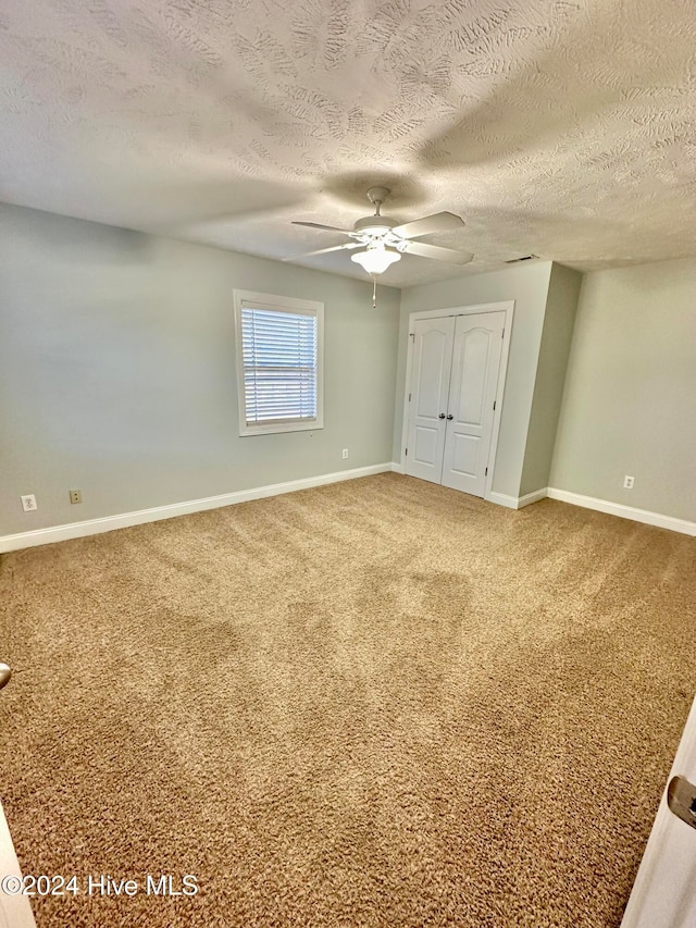 unfurnished bedroom featuring carpet flooring, ceiling fan, and a textured ceiling