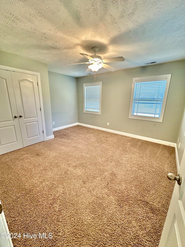 spare room featuring carpet flooring, a textured ceiling, and plenty of natural light