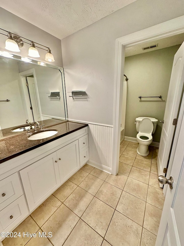 bathroom with tile patterned floors, vanity, a textured ceiling, and toilet