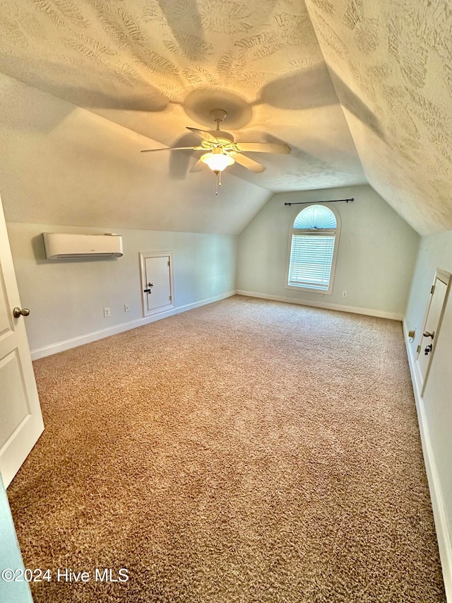 additional living space with carpet flooring, ceiling fan, an AC wall unit, a textured ceiling, and vaulted ceiling