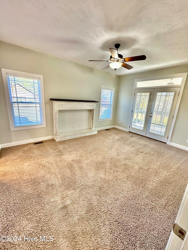 unfurnished living room featuring carpet flooring, ceiling fan, a textured ceiling, and french doors