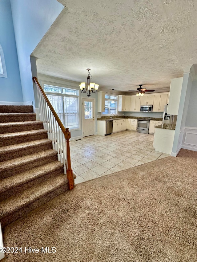 kitchen with stainless steel appliances, light colored carpet, a textured ceiling, decorative light fixtures, and white cabinets