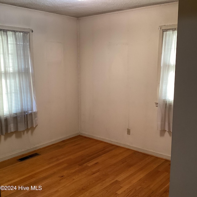 unfurnished room with crown molding, wood-type flooring, and a textured ceiling