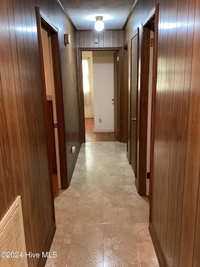 hallway with wood walls and a textured ceiling