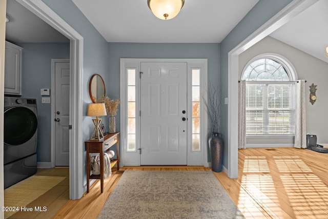 entryway featuring light hardwood / wood-style floors, lofted ceiling, and washer / dryer