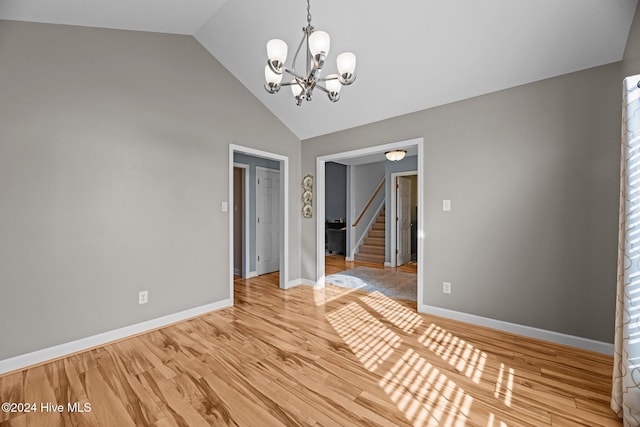 spare room with hardwood / wood-style floors, lofted ceiling, and a notable chandelier