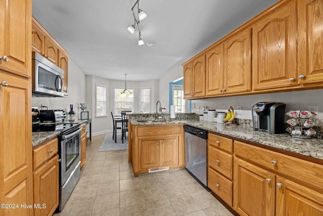 kitchen with stone counters, sink, hanging light fixtures, light tile patterned flooring, and appliances with stainless steel finishes