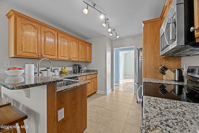 kitchen featuring a kitchen breakfast bar, appliances with stainless steel finishes, sink, light tile patterned floors, and dark stone countertops