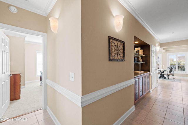 corridor featuring ornamental molding and light tile patterned floors