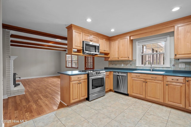 kitchen featuring sink, appliances with stainless steel finishes, tasteful backsplash, light hardwood / wood-style floors, and kitchen peninsula