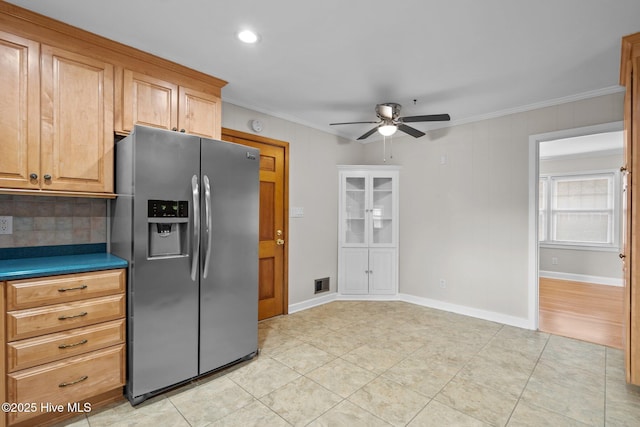 kitchen featuring backsplash, crown molding, ceiling fan, stainless steel fridge, and light tile patterned floors