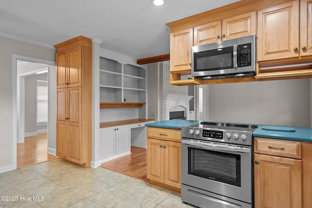 kitchen with stainless steel appliances, crown molding, light brown cabinetry, a fireplace, and light tile patterned flooring