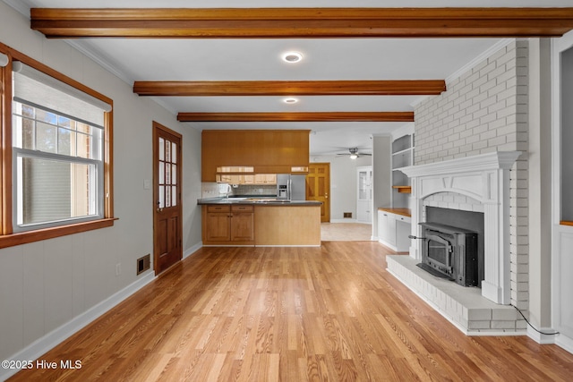 unfurnished living room featuring built in shelves, ceiling fan, crown molding, beam ceiling, and light hardwood / wood-style floors