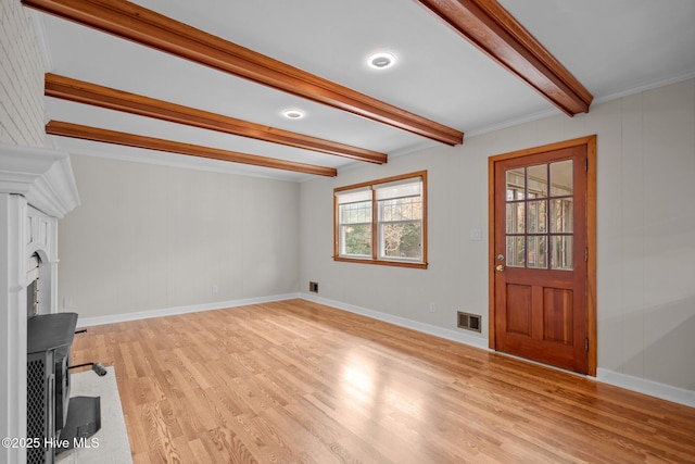 foyer entrance featuring beam ceiling, crown molding, and light hardwood / wood-style flooring