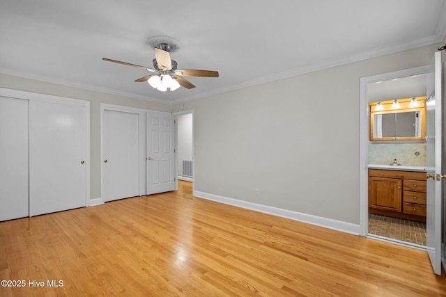 unfurnished bedroom featuring ceiling fan, ornamental molding, connected bathroom, and multiple closets