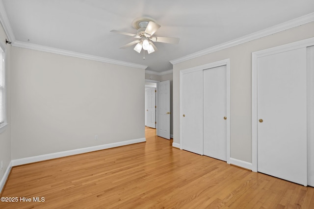 unfurnished bedroom with ceiling fan, light wood-type flooring, ornamental molding, and multiple closets