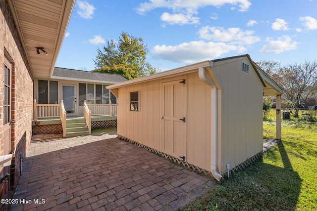 view of outbuilding featuring a sunroom and a yard