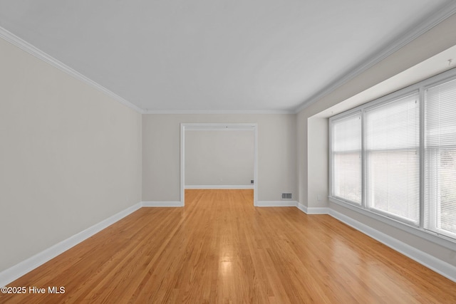 empty room with light hardwood / wood-style flooring, a wealth of natural light, and ornamental molding