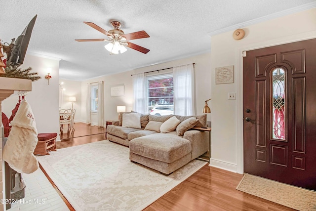 living room featuring ceiling fan, crown molding, a textured ceiling, and hardwood / wood-style flooring