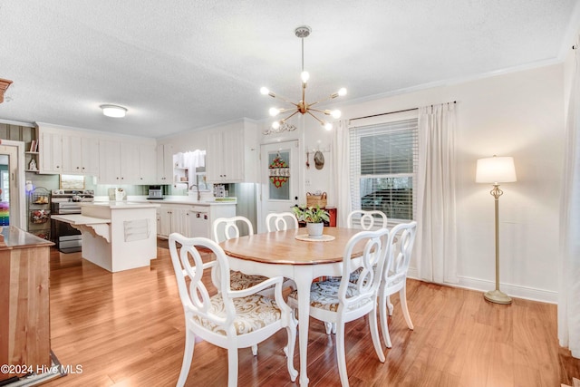 dining room with sink, a chandelier, light hardwood / wood-style floors, a textured ceiling, and ornamental molding