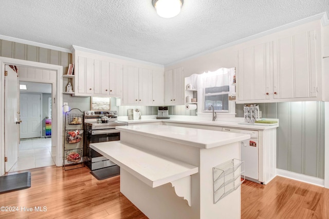 kitchen with dishwasher, a center island, light hardwood / wood-style floors, stainless steel range with electric stovetop, and white cabinets