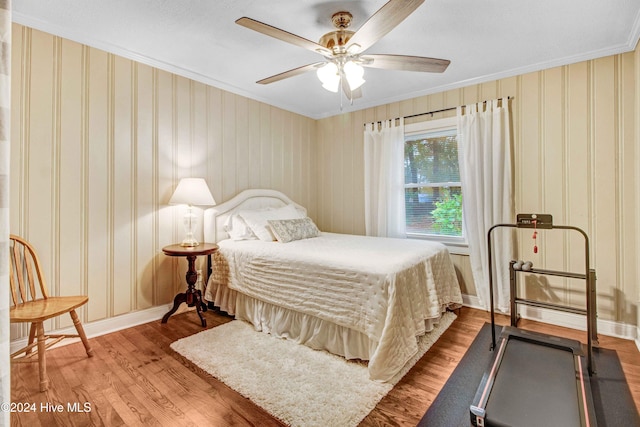 bedroom with wood-type flooring, ceiling fan, and crown molding