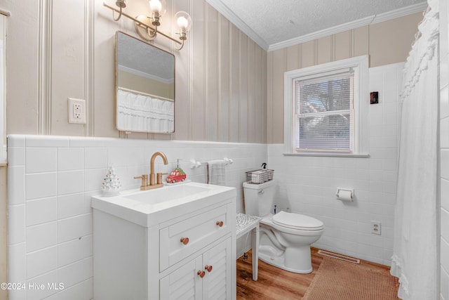 bathroom with wood-type flooring, toilet, vanity, tile walls, and ornamental molding