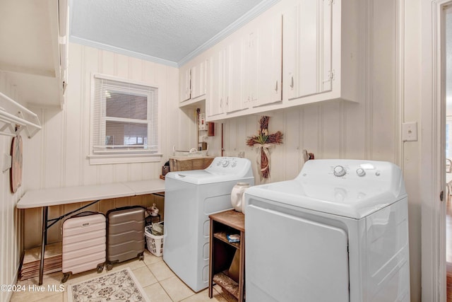 clothes washing area featuring cabinets, washing machine and dryer, a textured ceiling, light tile patterned flooring, and ornamental molding