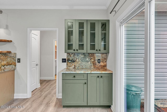 kitchen featuring backsplash, green cabinets, light hardwood / wood-style flooring, ornamental molding, and light stone counters